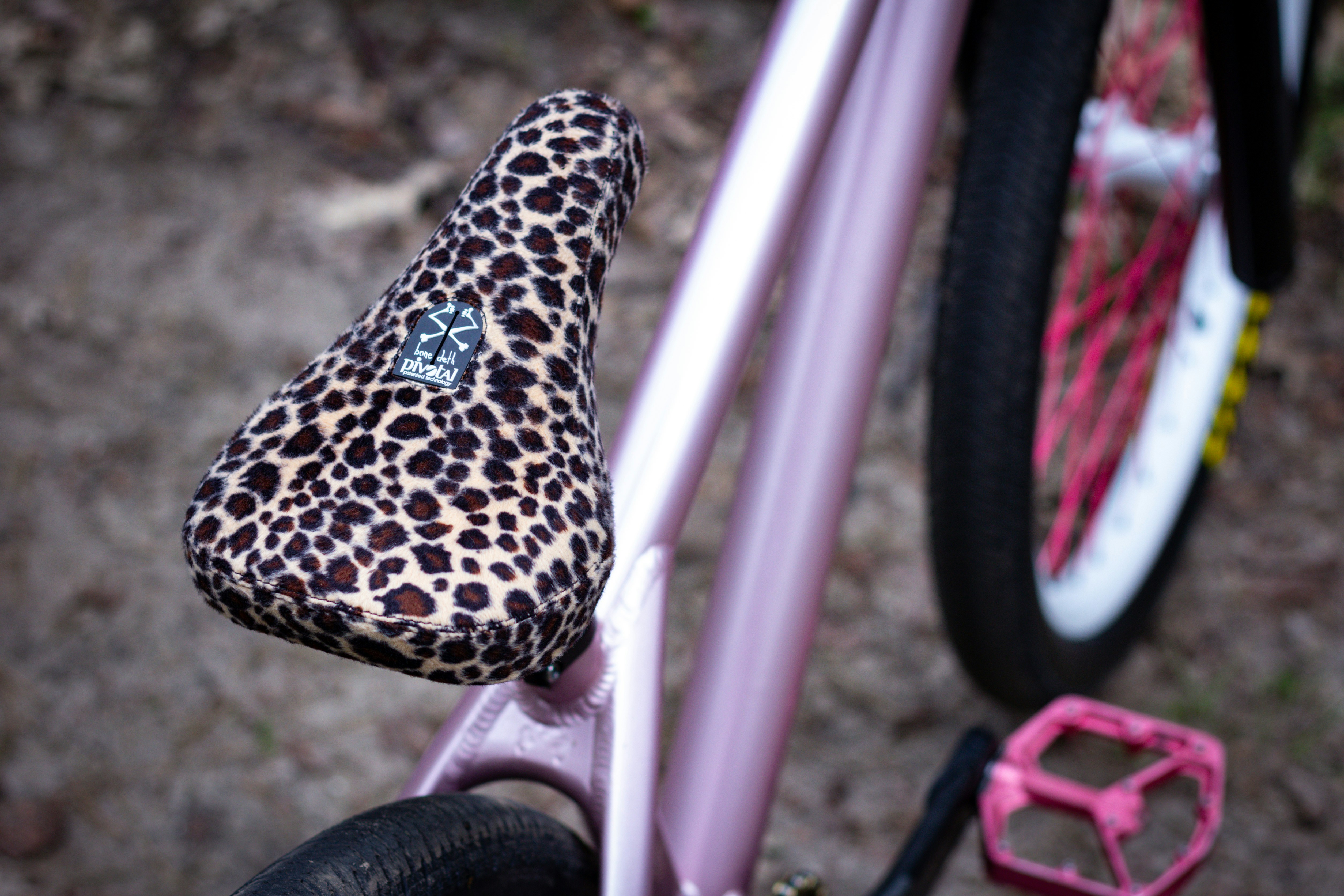 A leopard-print seat sits on a pink bicycle.
