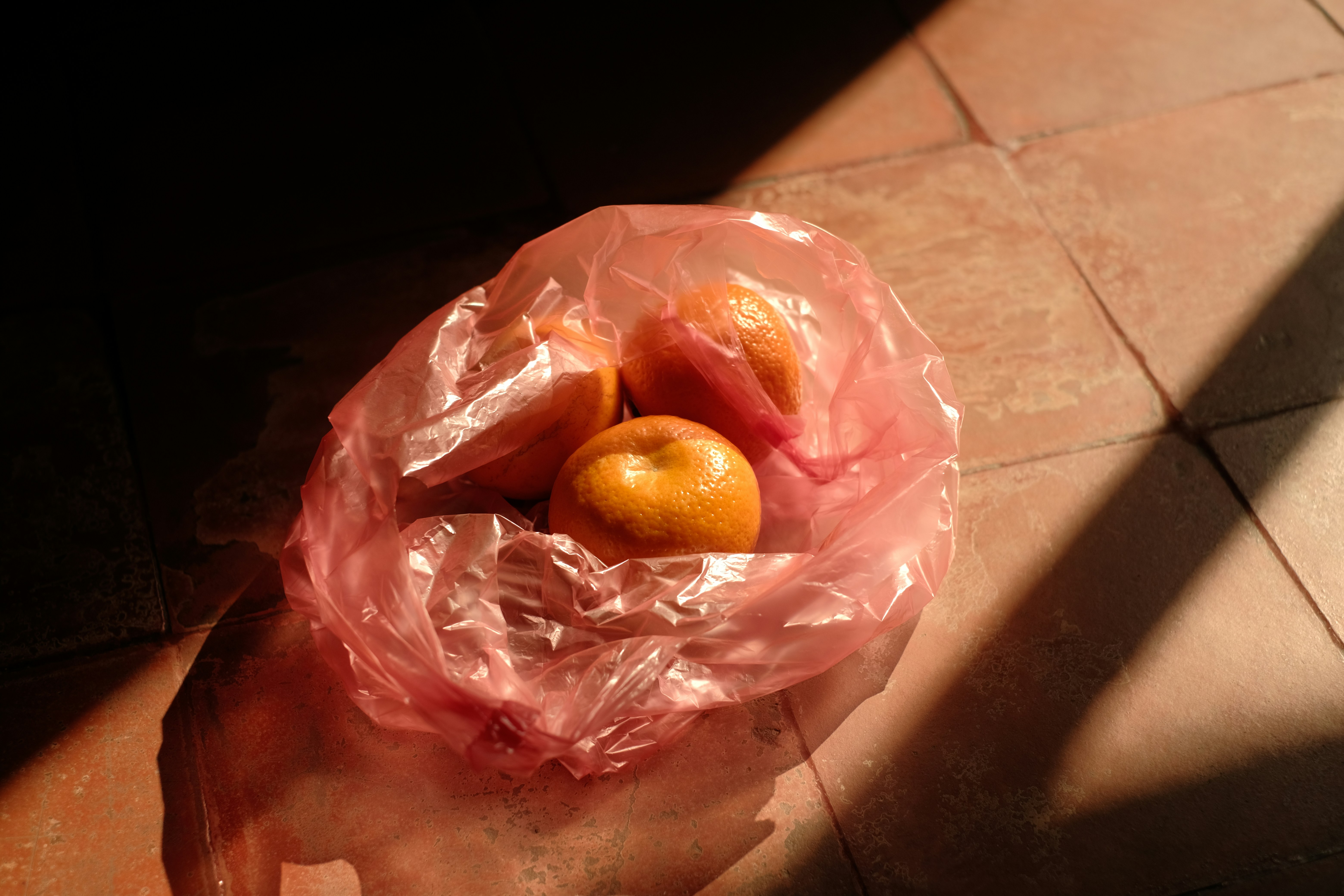 Tangerines rest in a pink plastic bag.