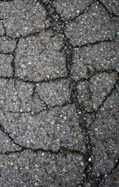 Cracked asphalt pavement with visible lines and texture.