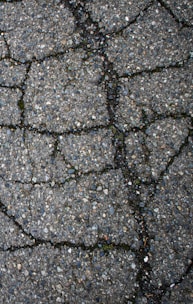 Cracked asphalt pavement with visible lines and texture.