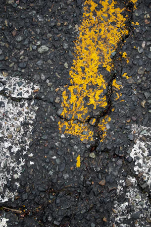 Yellow and white lines on cracked pavement