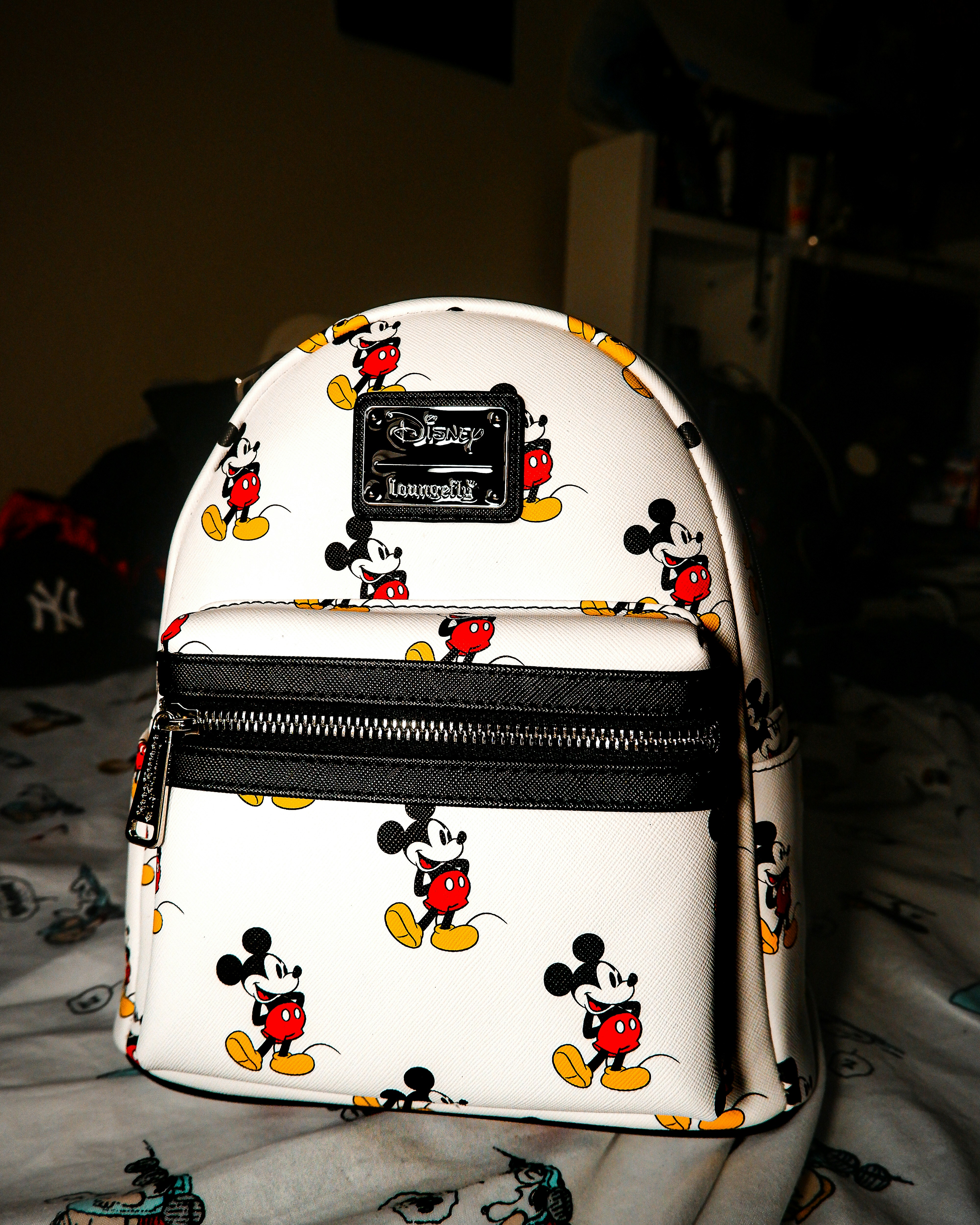 A mickey mouse backpack sits on a bed.