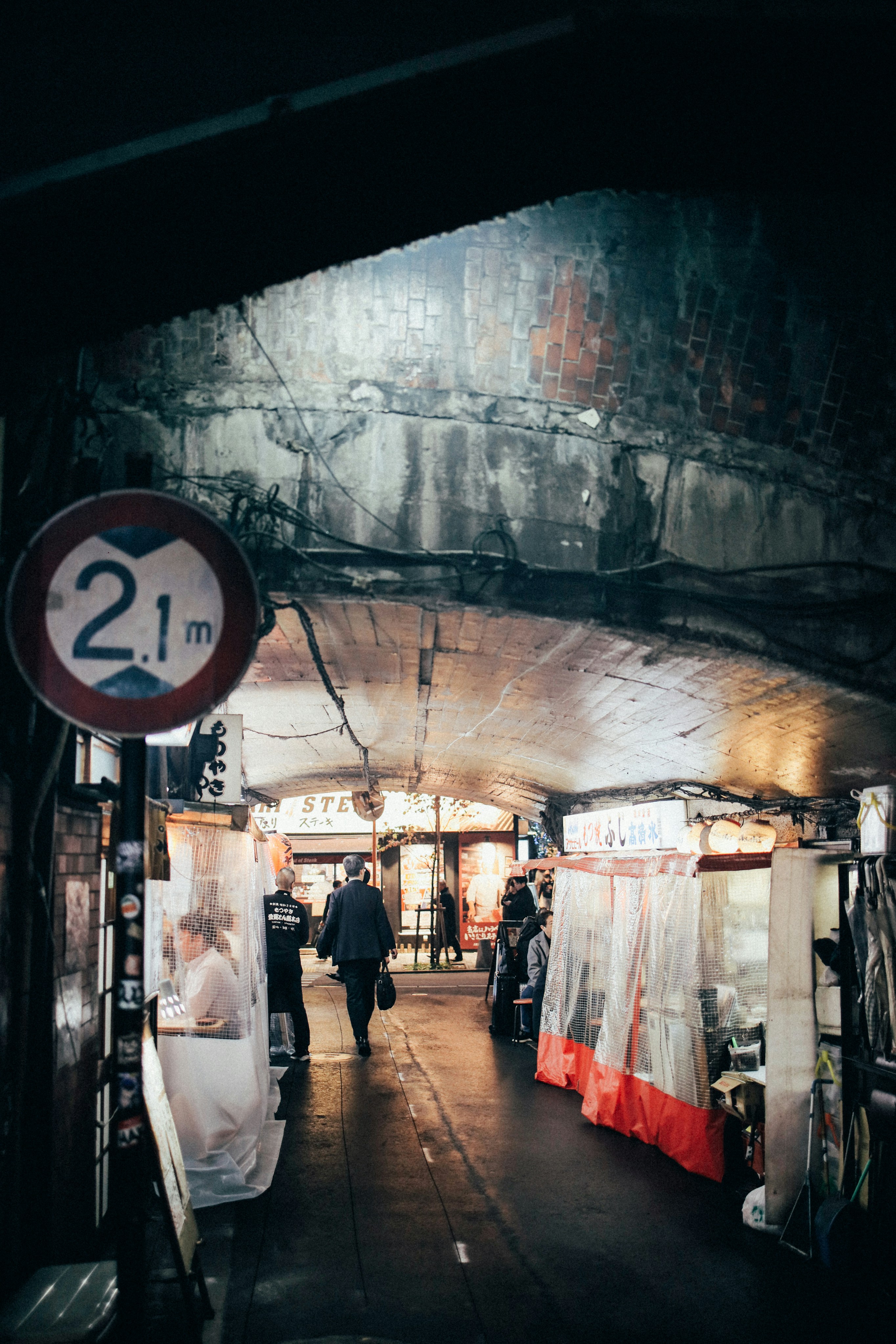Pedestrians in a narrow Tokyo alley lined with small shops