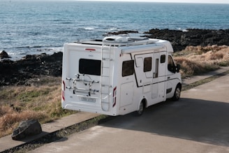 A white rv parked near the ocean.