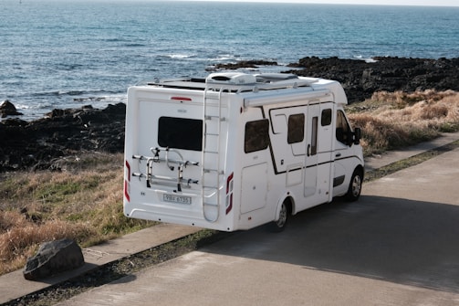 A white rv parked near the ocean.