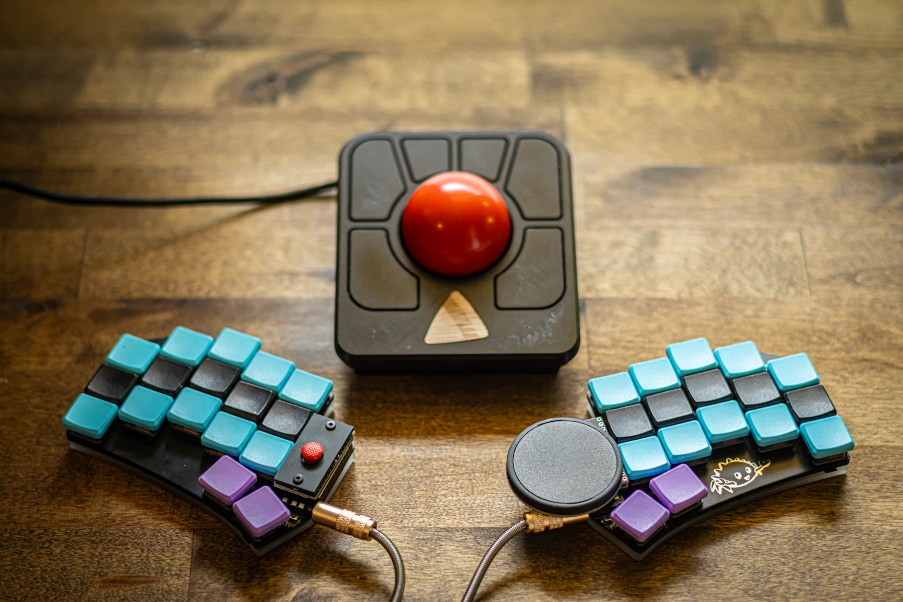 The two halves of a split keyboard and a trackball on a wooden desk