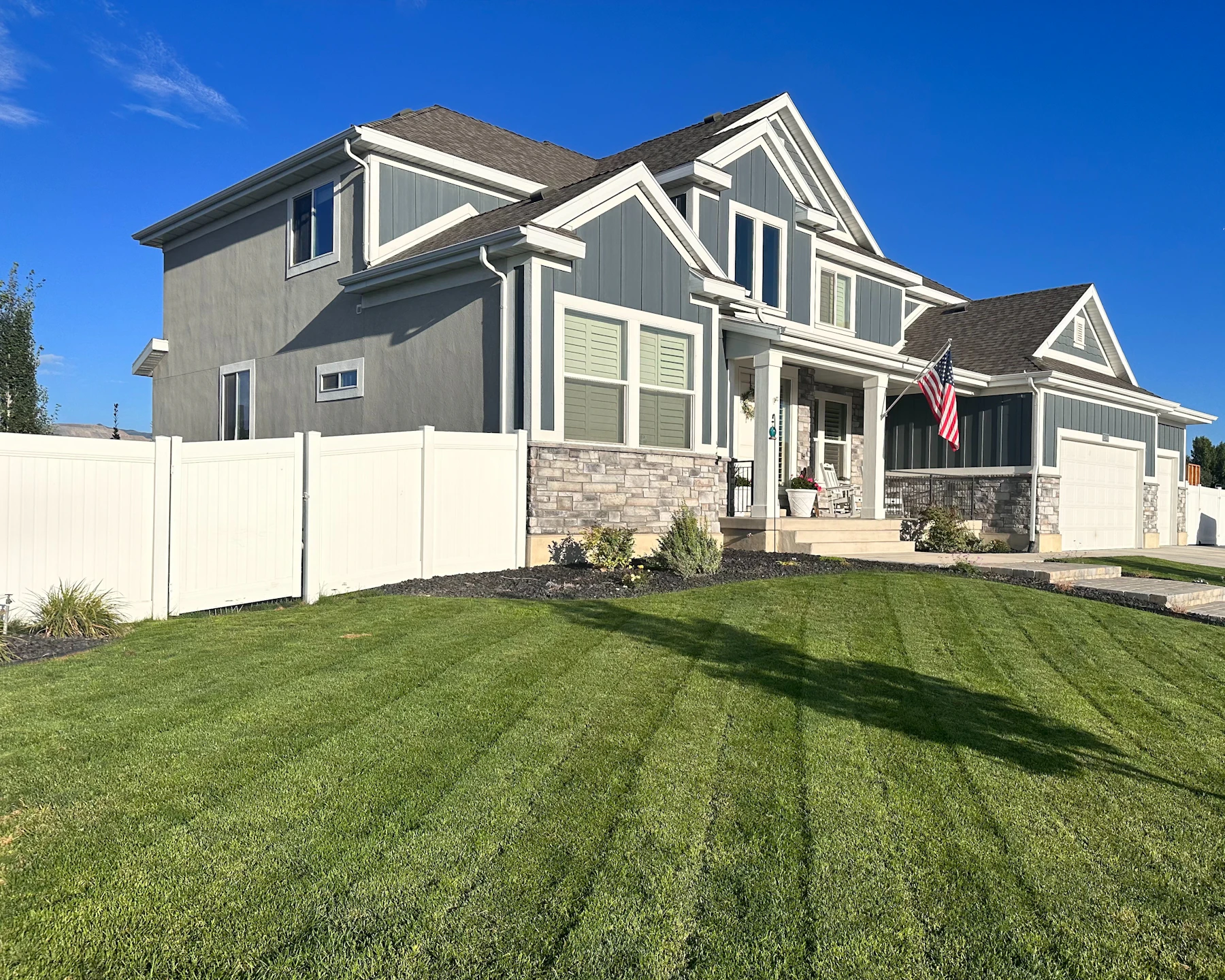 Contemporary suburban home with diagonal mowing stripes on the front lawn, crisp mulch beds, and a walk to the porch—curb appeal neighbors notice