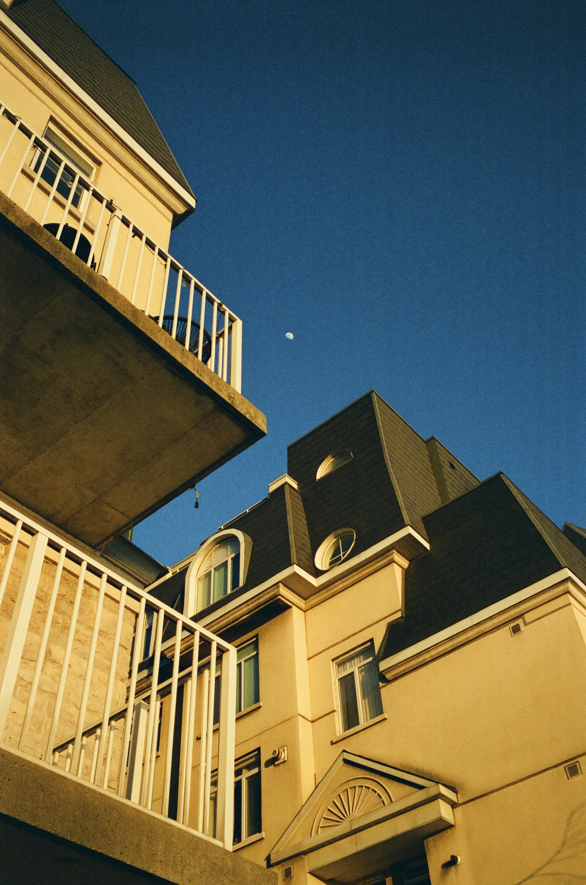 Buildings' rooftops and balconies against a clear blue sky.