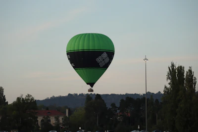 A green hot air balloon floats in the sky.