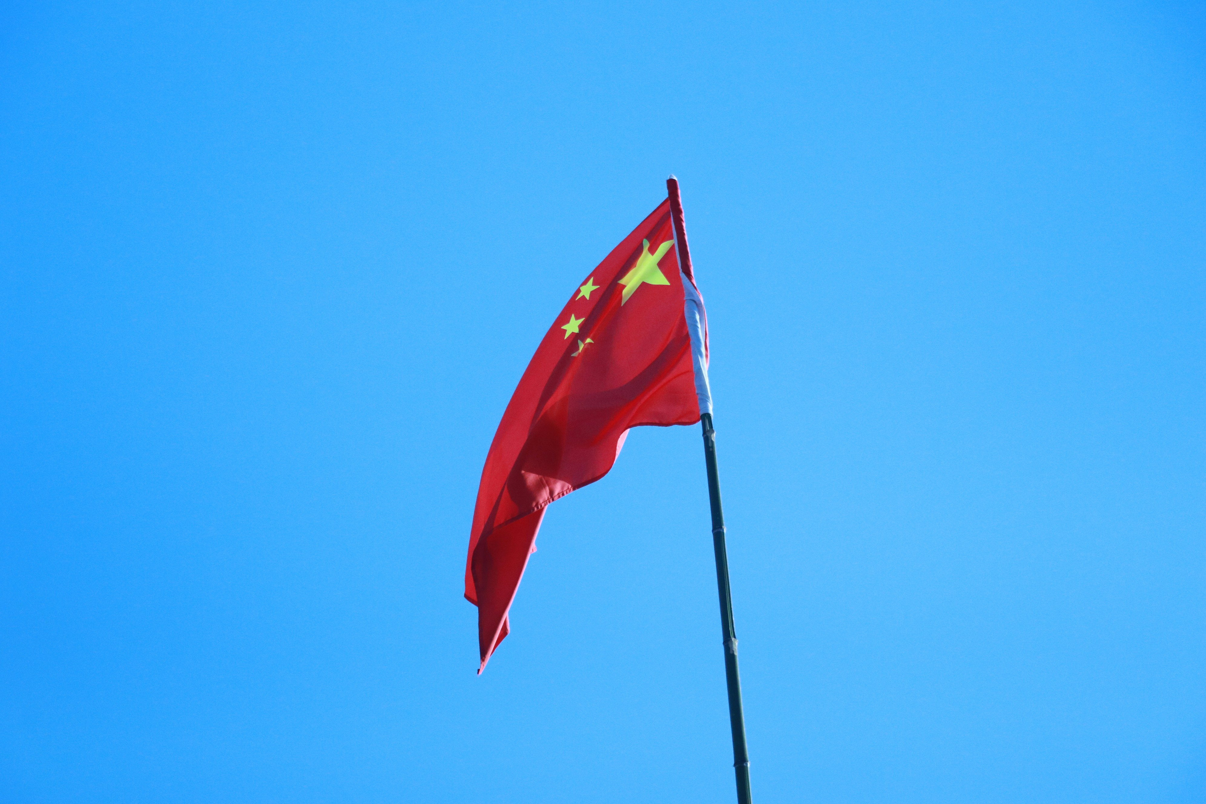 The chinese flag waves against a blue sky.