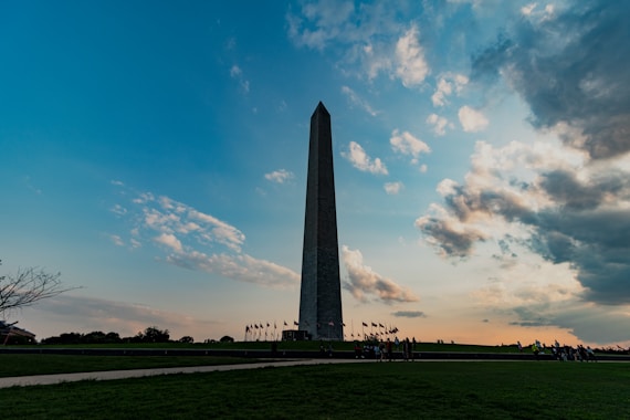 The washington monument stands tall beneath cloudy skies.