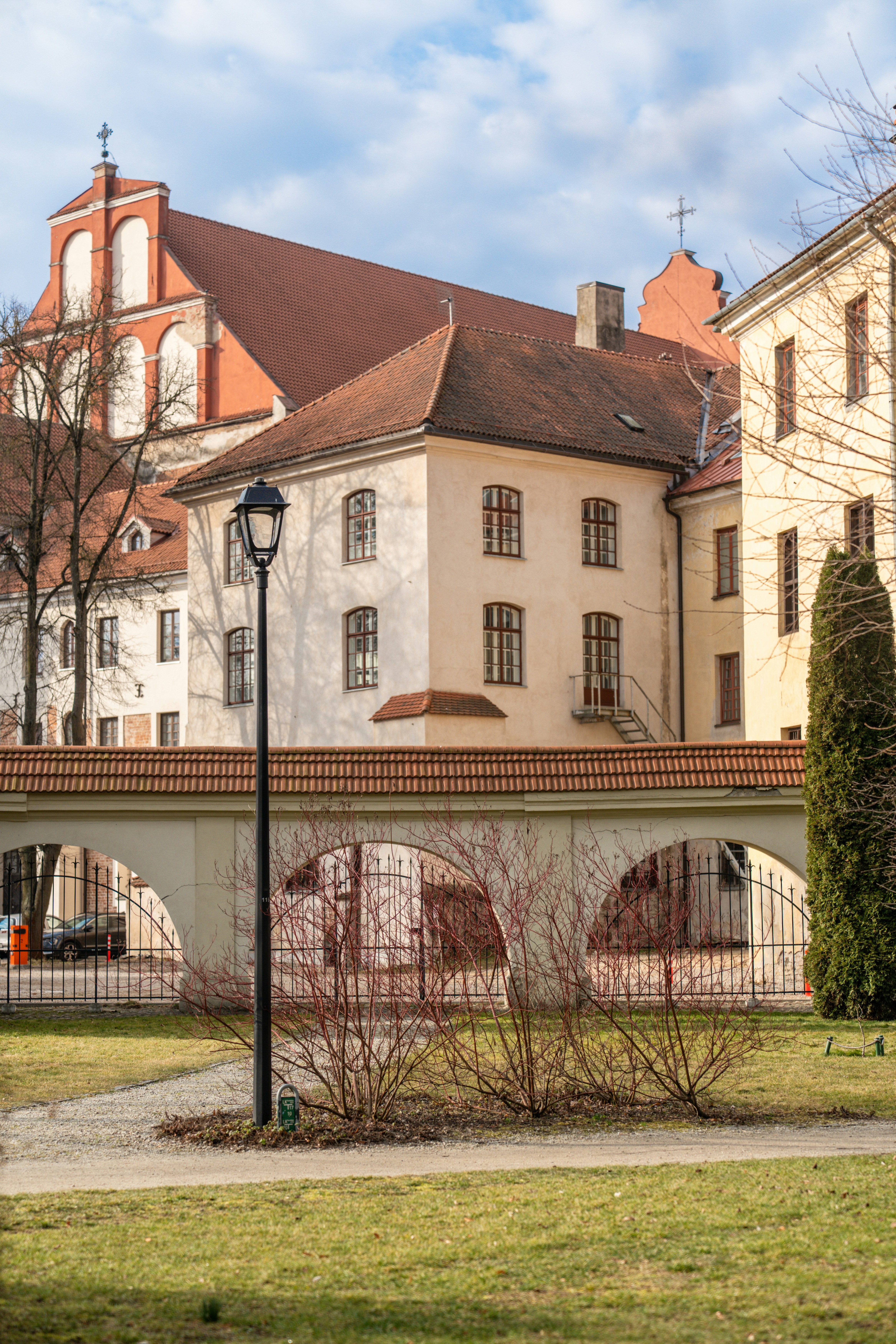 Buildings with arched walkway under a cloudy sky.