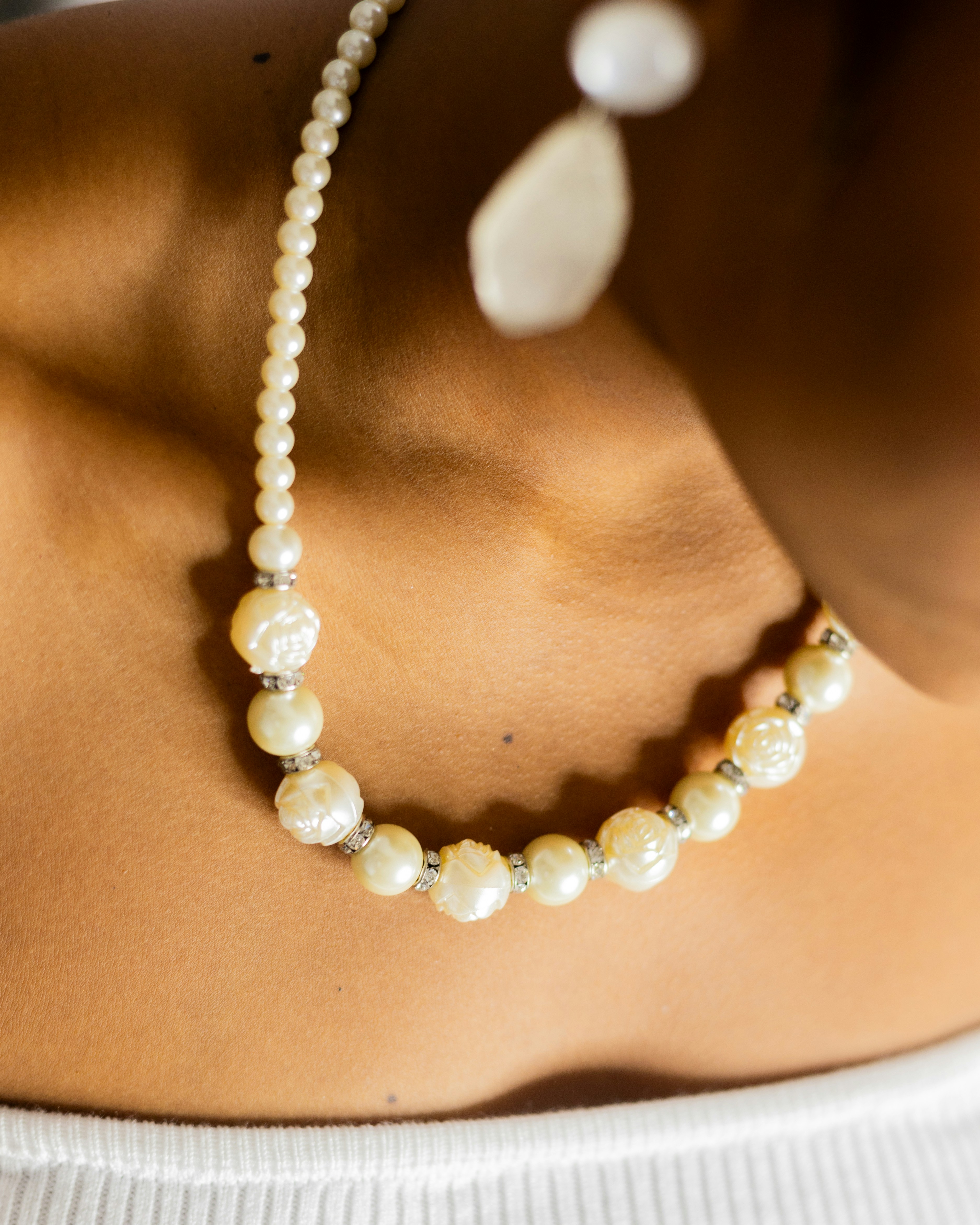 Woman in white dressing showing here pearl necklace