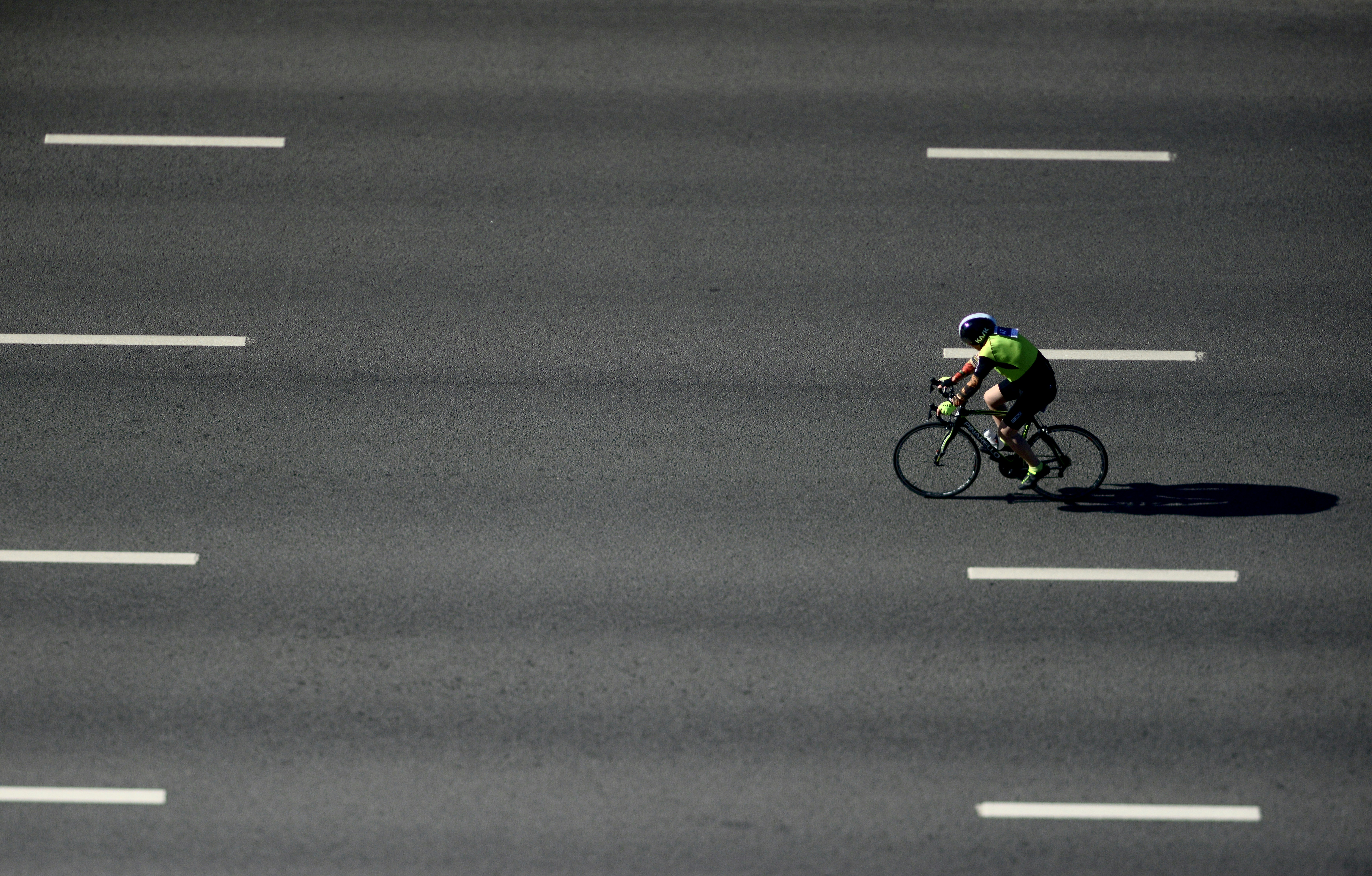 Cyclist rides down a wide, empty road.