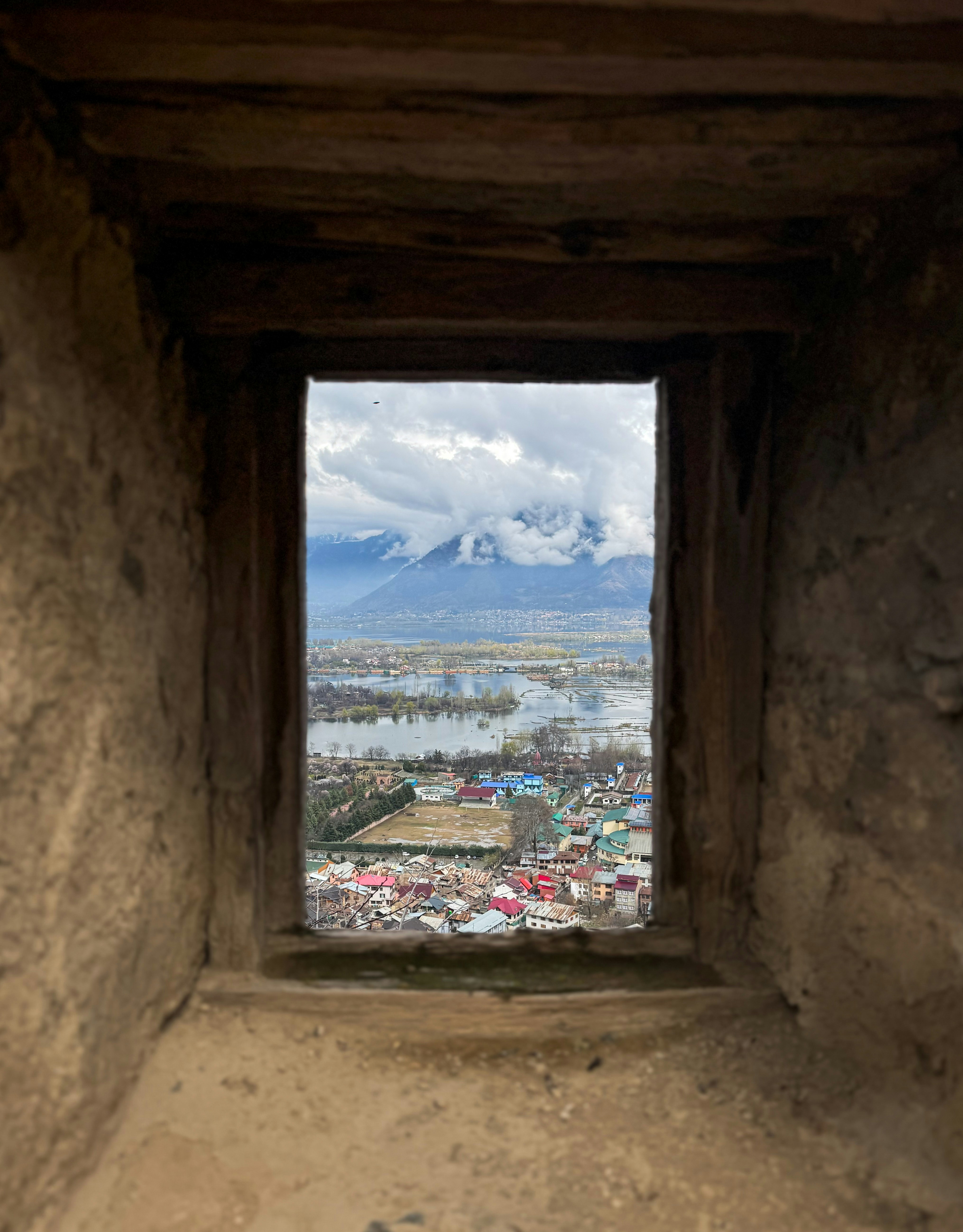 Blick durch ein Fenster auf die Berge und die Stadt.