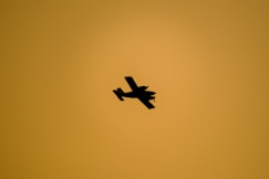 A silhouette of an airplane against the yellow sky.