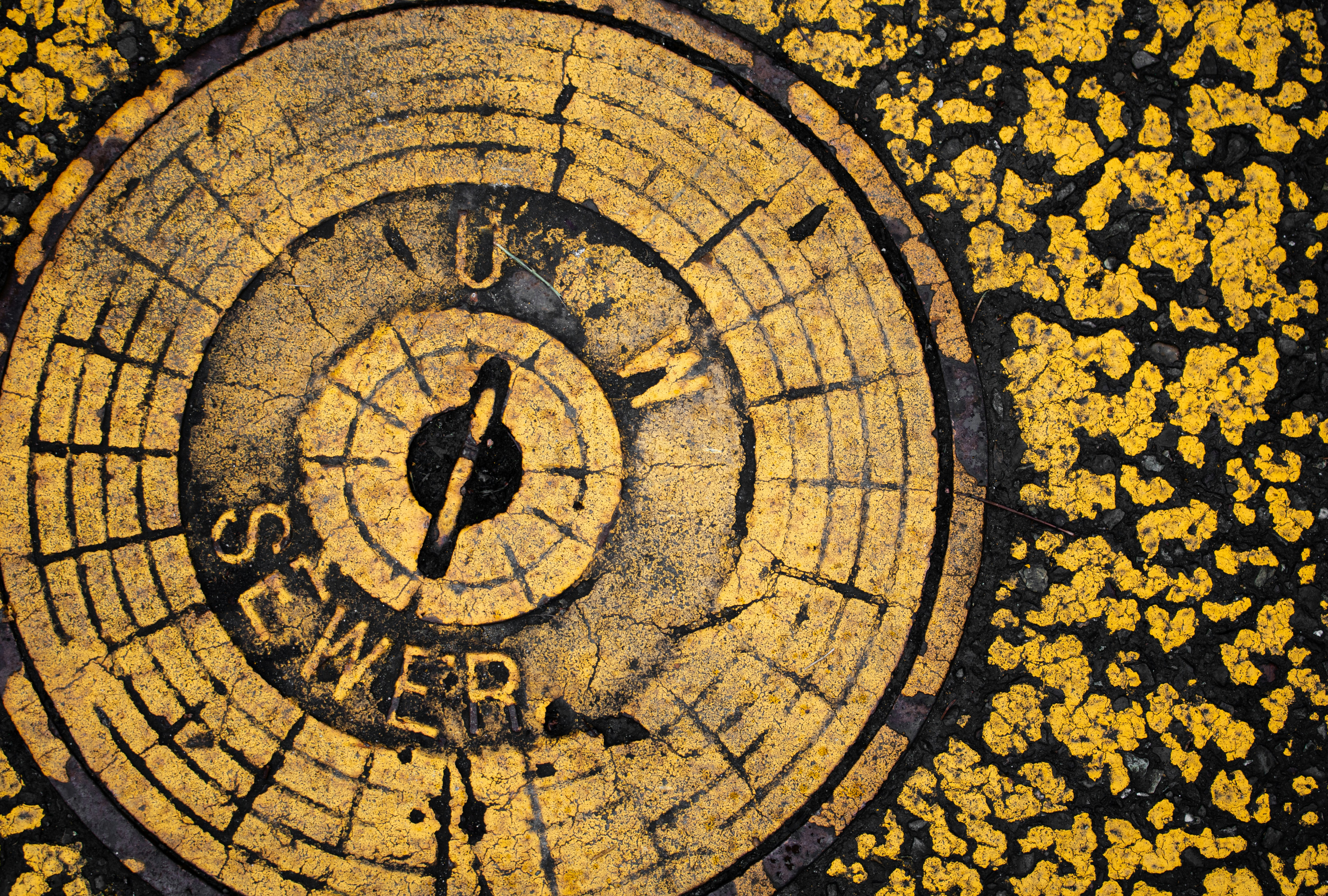 A yellow sewer cover in a concrete surface.