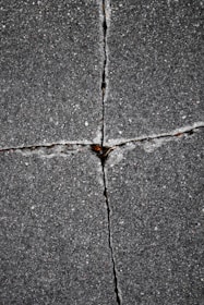 Cracked pavement forms a cross-like pattern.