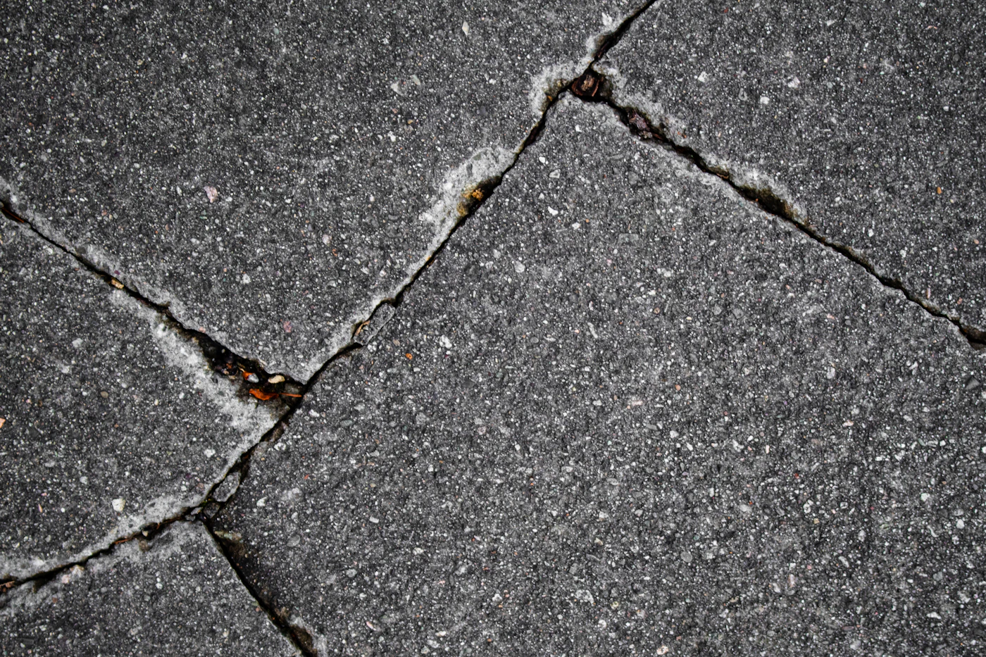 Cracked concrete sidewalk pavement close-up.
