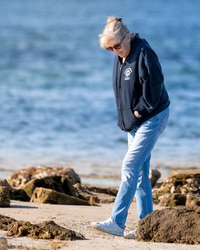 Woman walks along a beach near water.