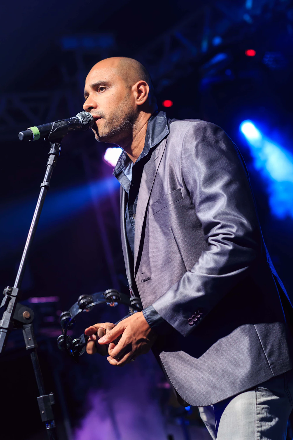 A bald man sings into a microphone.