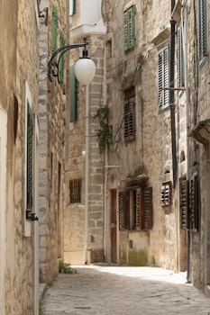 Narrow stone alleyway between old shuttered houses
