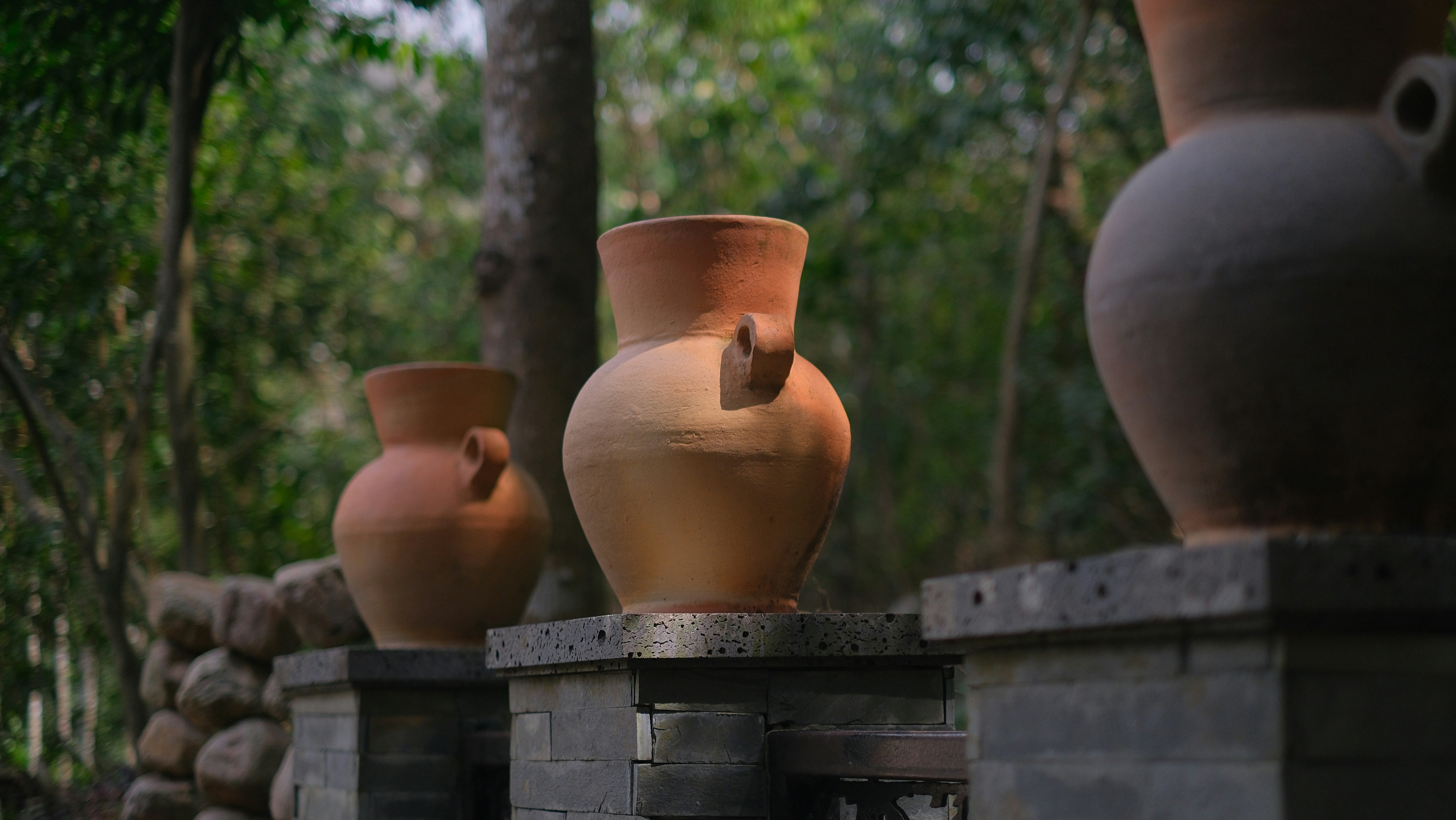 Clay pots decorate a wall with a forest backdrop.