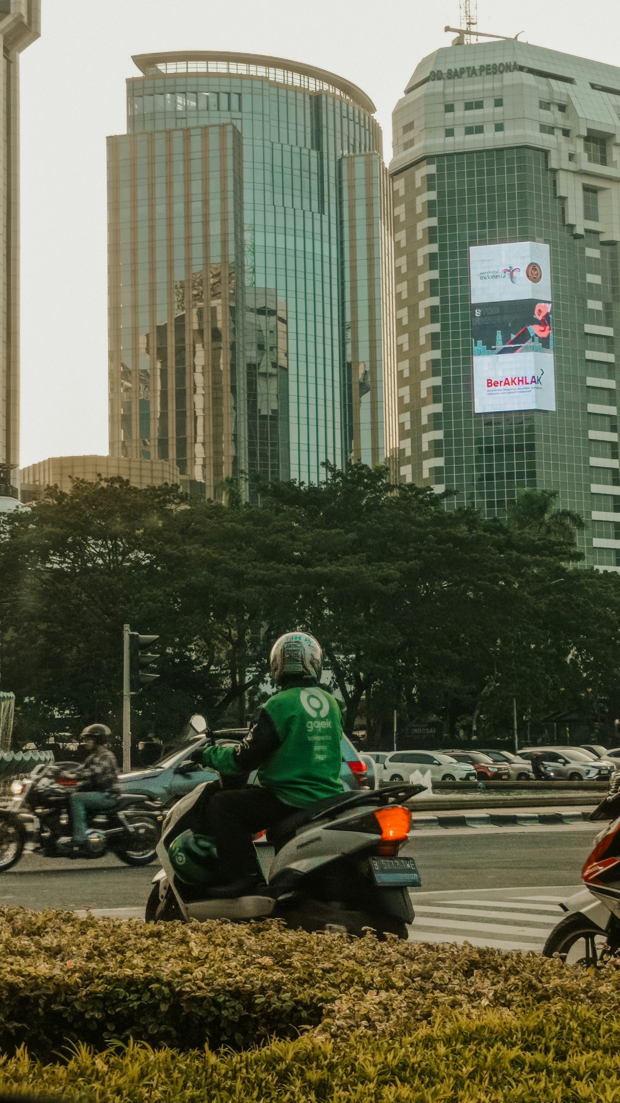 A gojek driver on a motorcycle in a city.