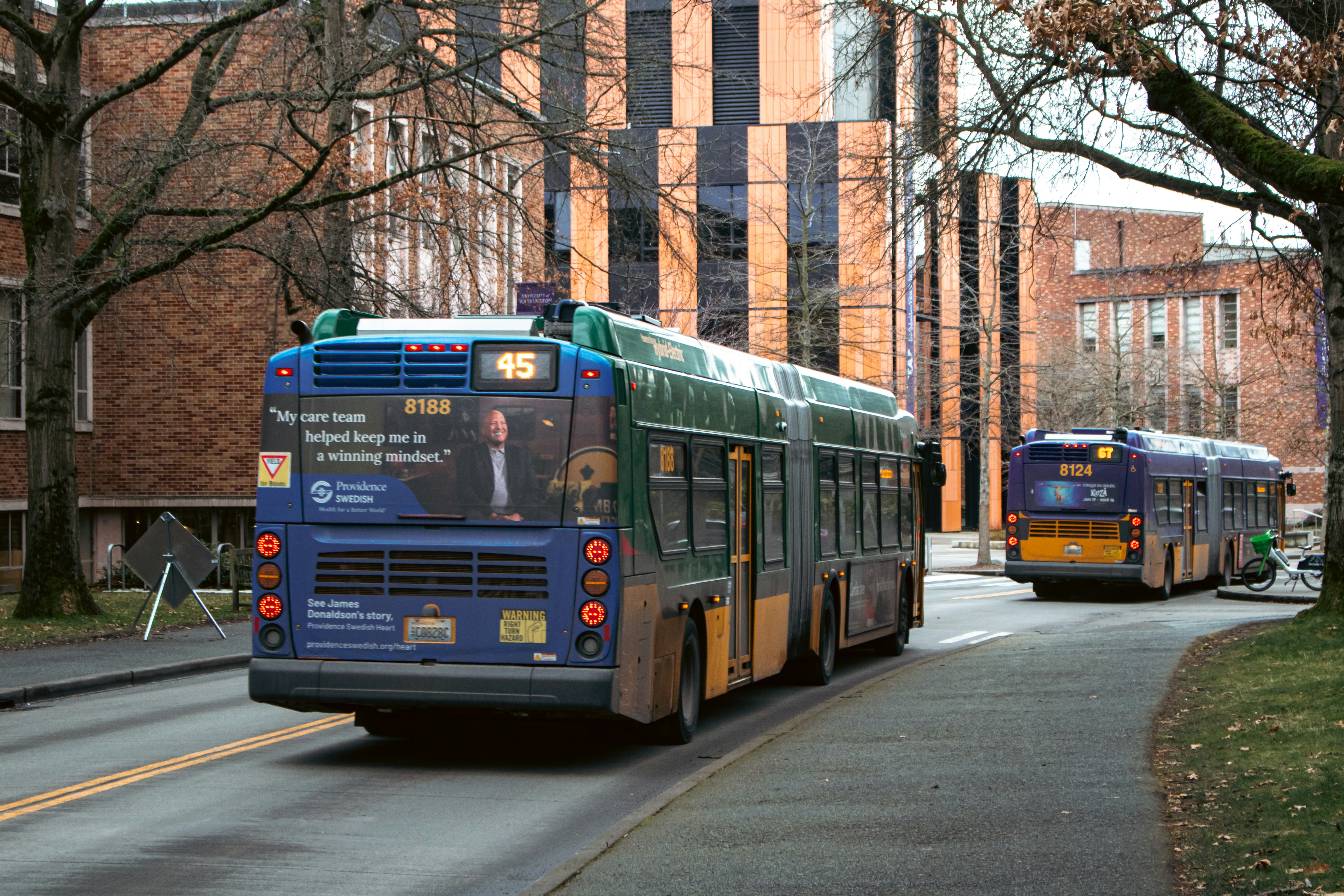 Buses drive on a city street.