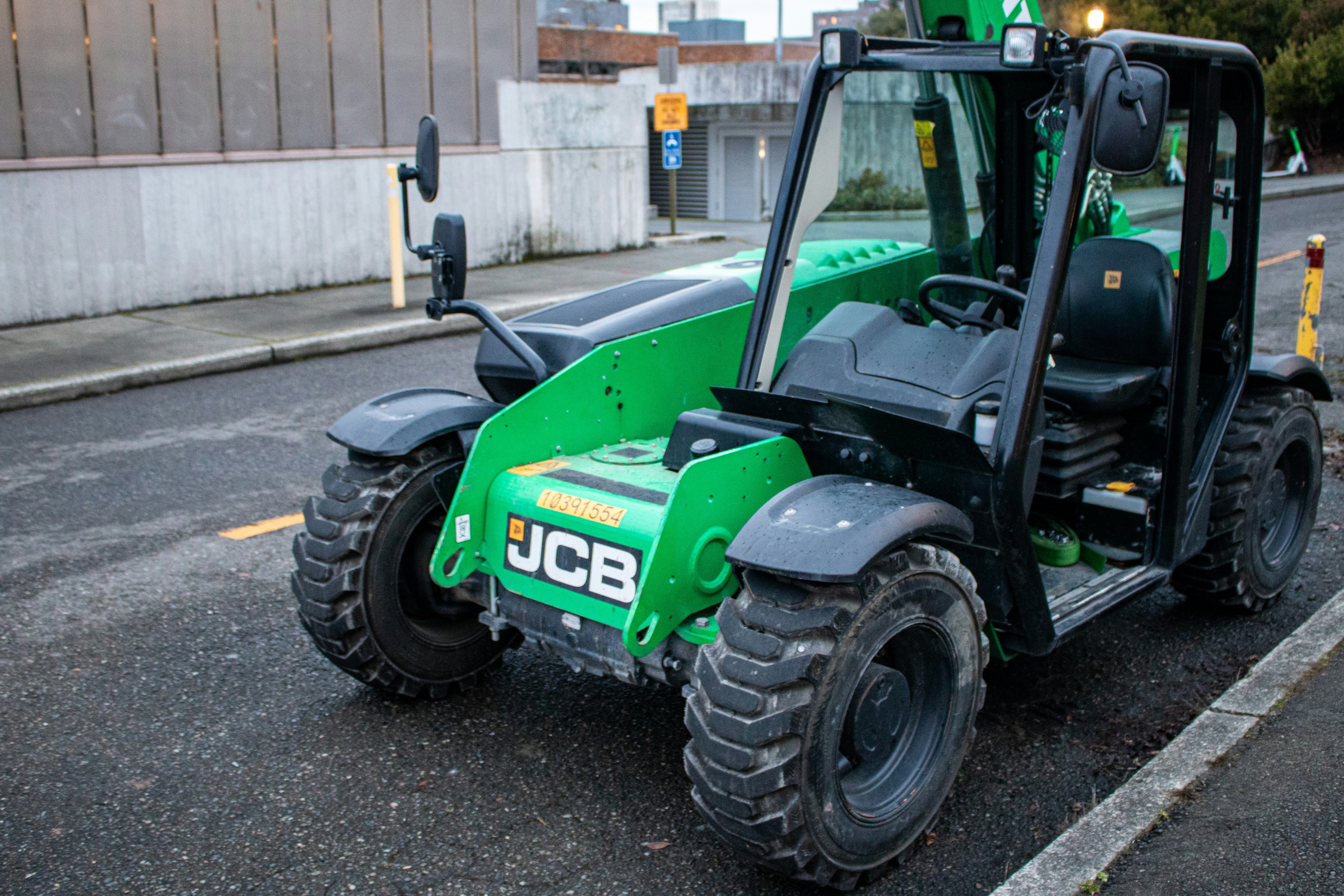 A green jcb telehandler sits on a street.