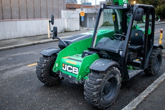 A green jcb telehandler sits on a street.