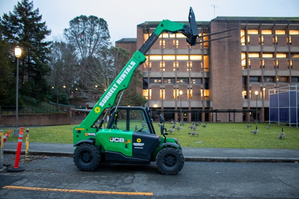 A green telehandler is parked on a road.