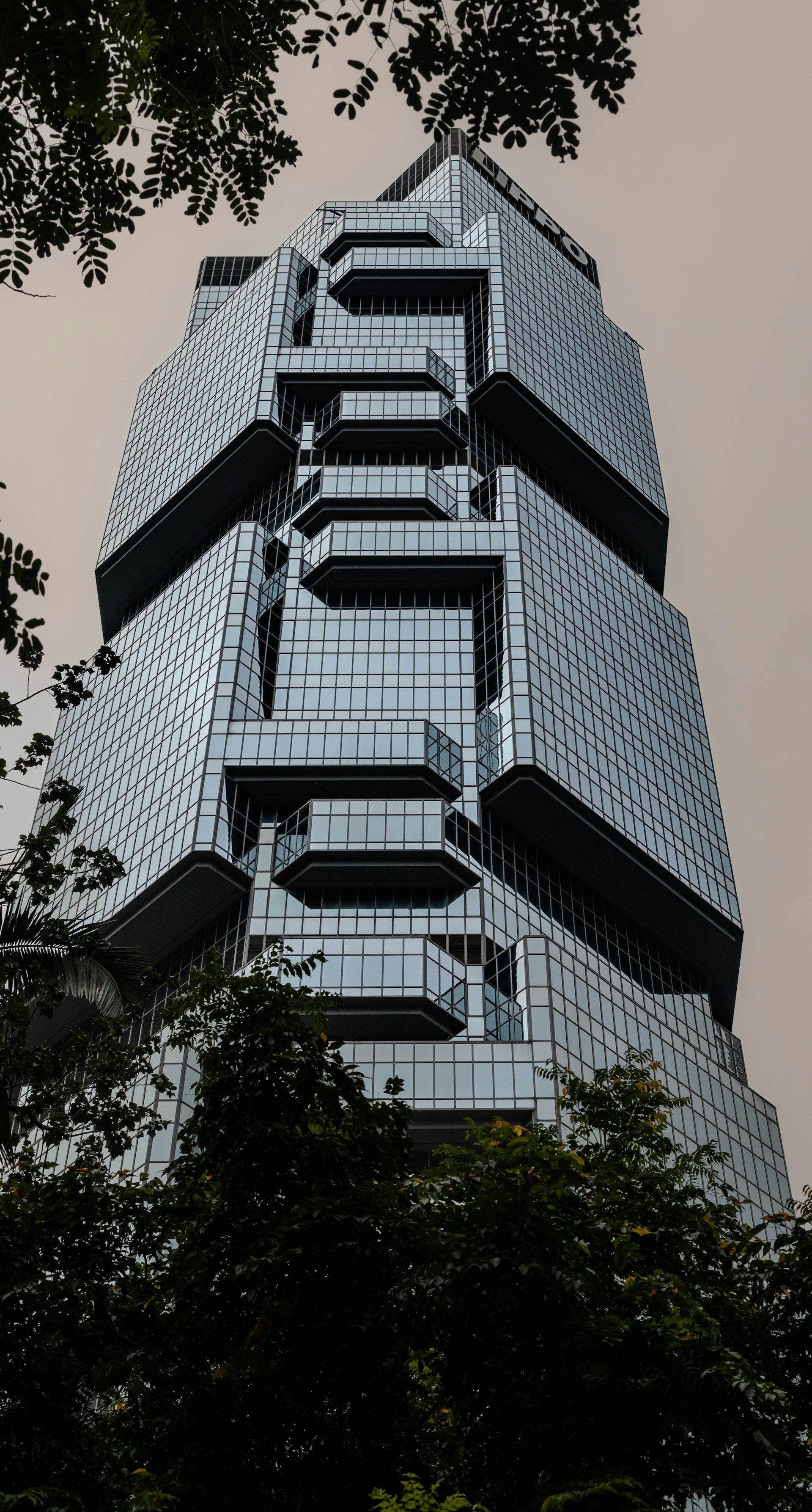 A modern skyscraper rises above the trees.