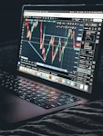 Laptop displays a stock market trading chart.