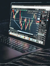 Laptop displays a stock market trading chart.