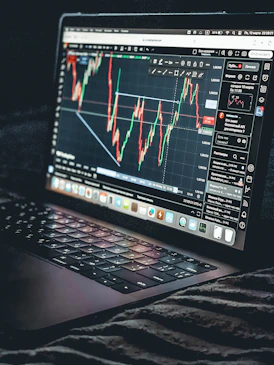 Laptop displays a stock market trading chart.