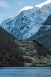 Houses sit peacefully beneath a snowy mountain.