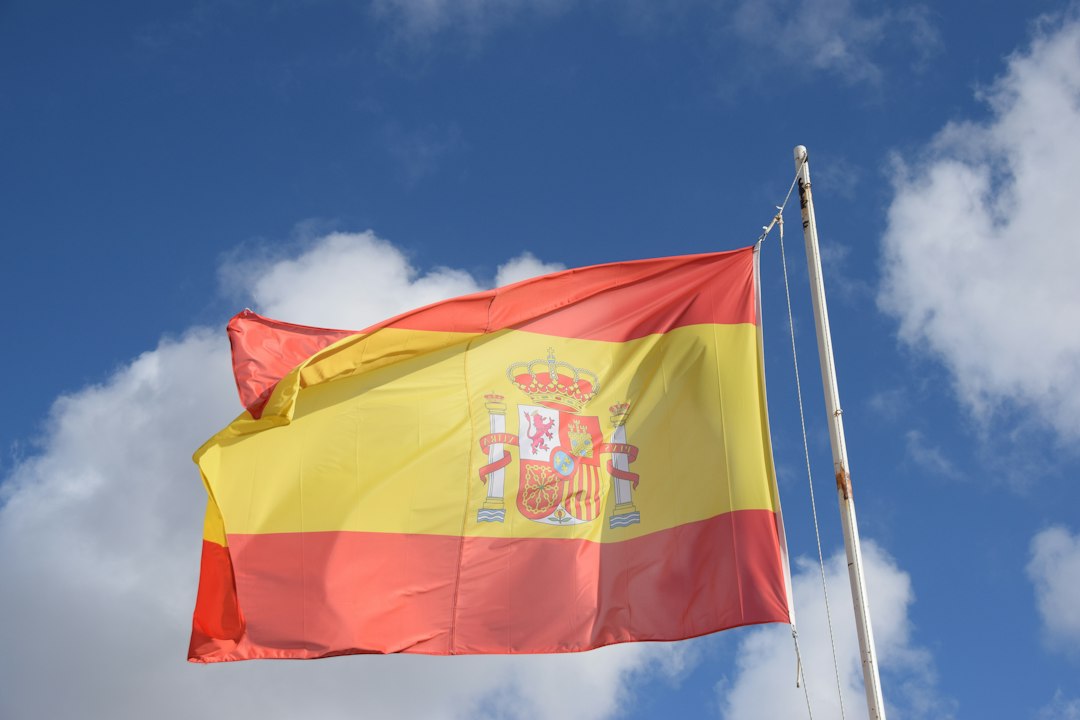 The spanish flag waves proudly against a blue sky.