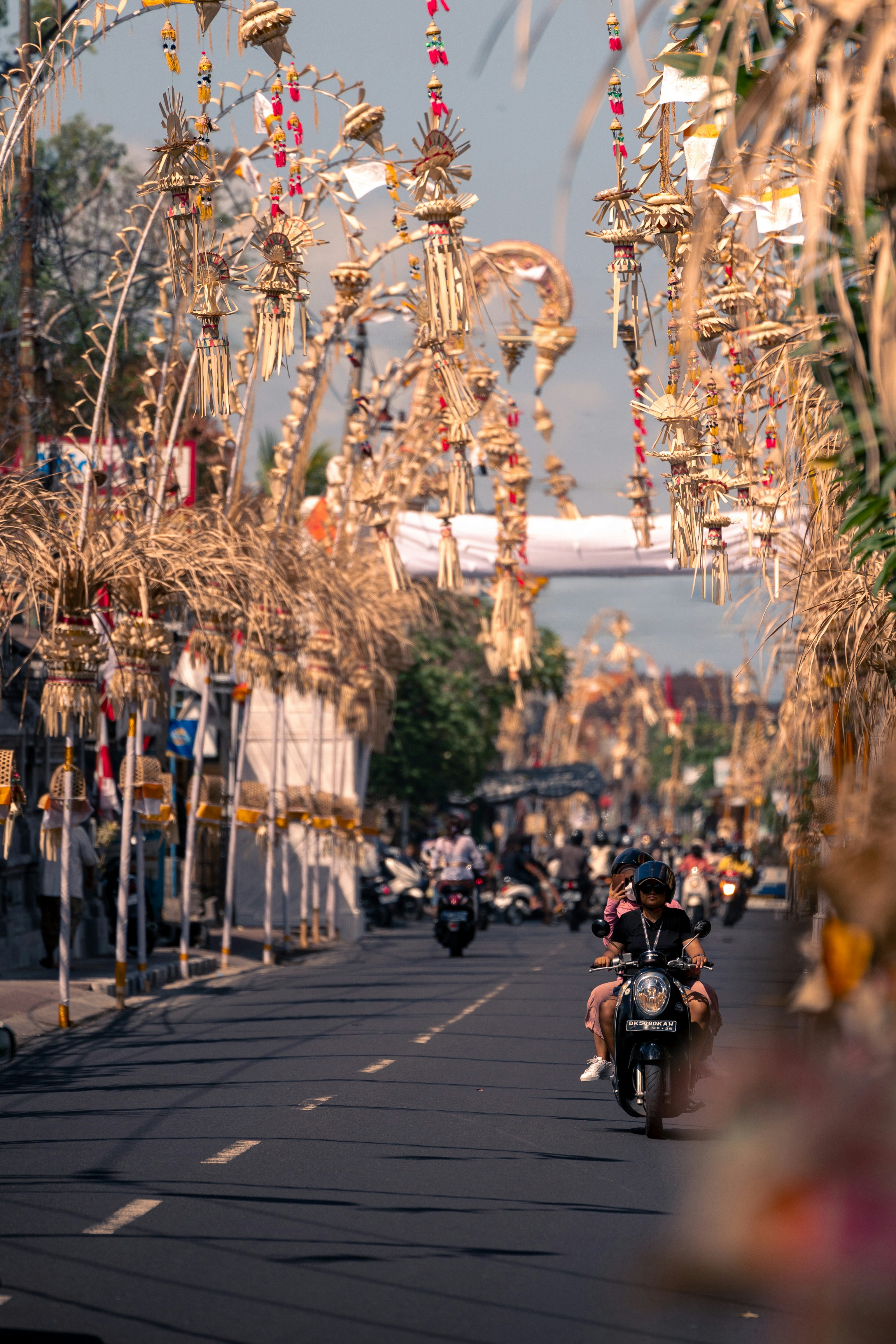 Street adorned with balinese decorations and scooters.