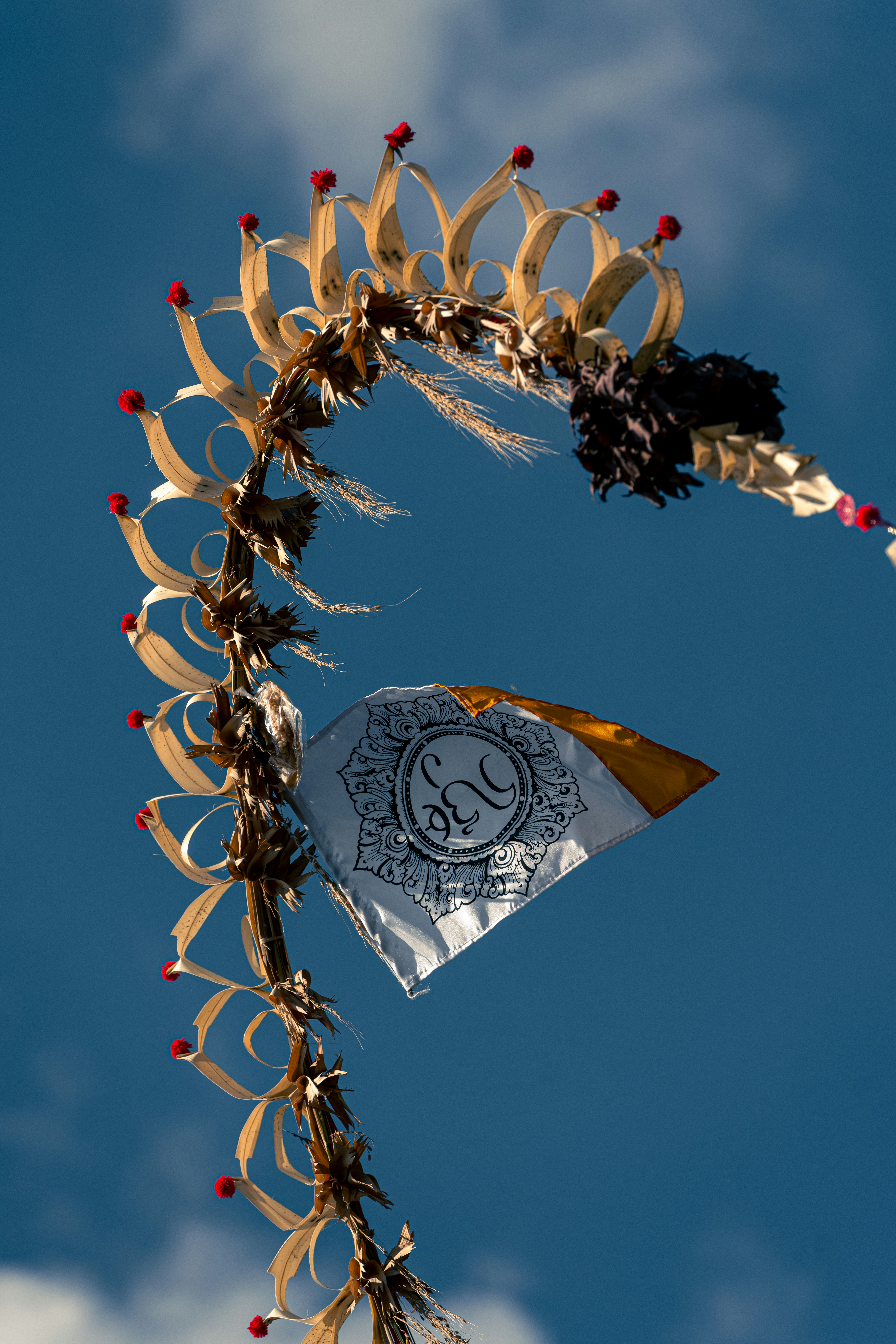 A balinese penjor against a bright, blue sky.