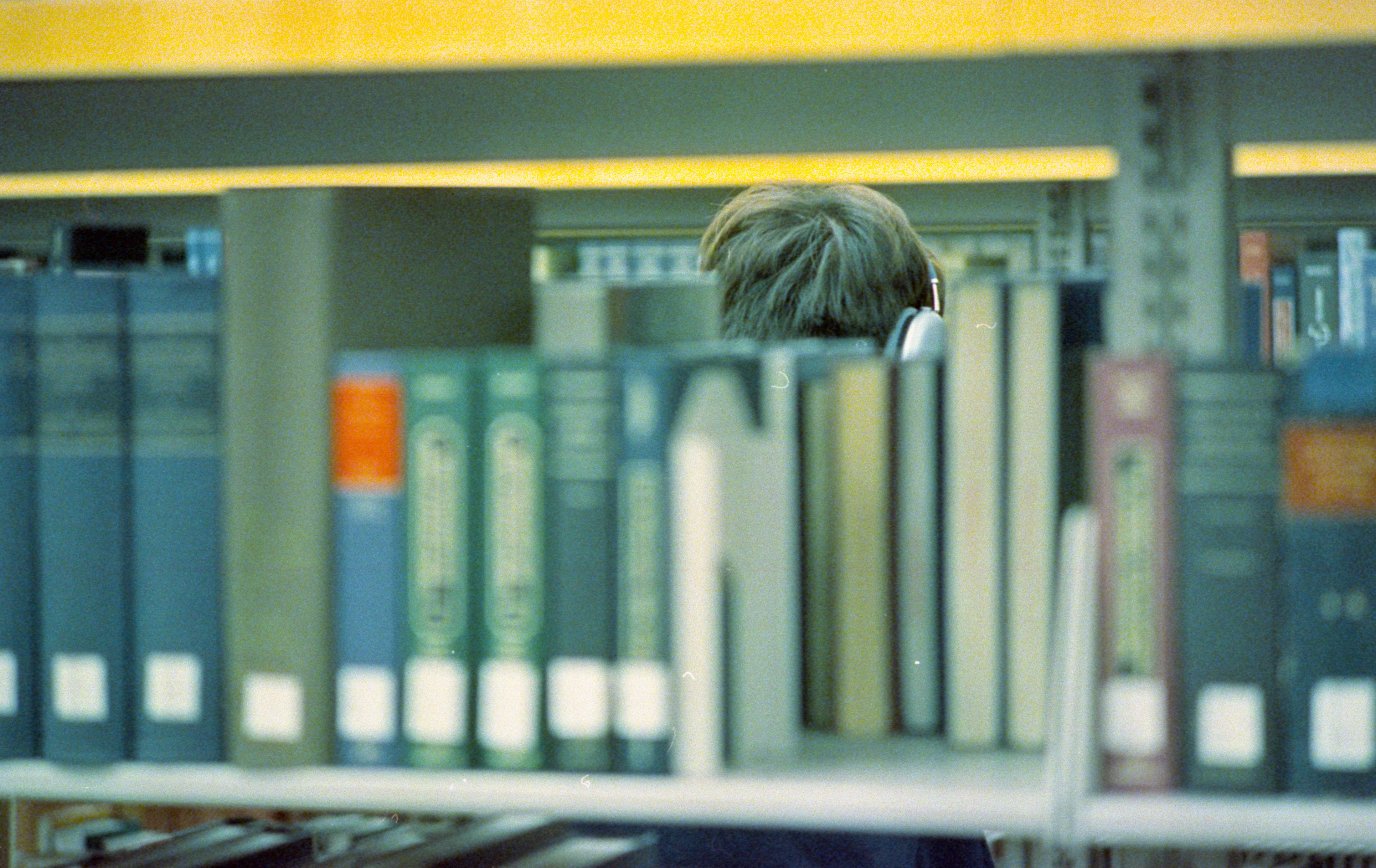 एक युवा छात्र तनावग्रस्त होकर पढ़ाई कर रहा है, उसके चारों ओर किताबें बिखरी हुई हैं।