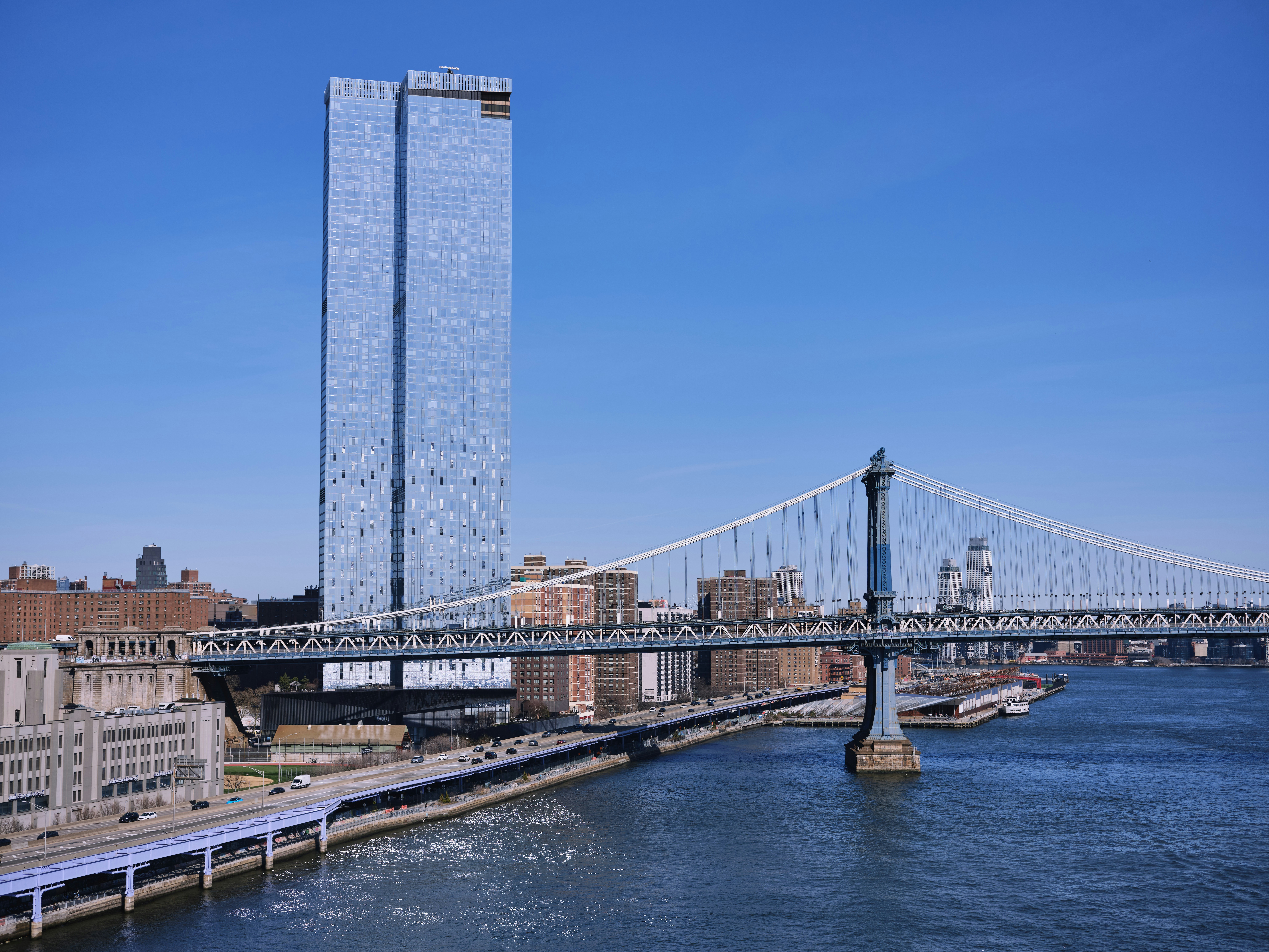 A tall tower sits near a large suspension bridge.