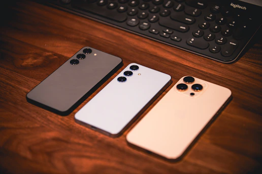 Three smartphones are on a wooden surface.