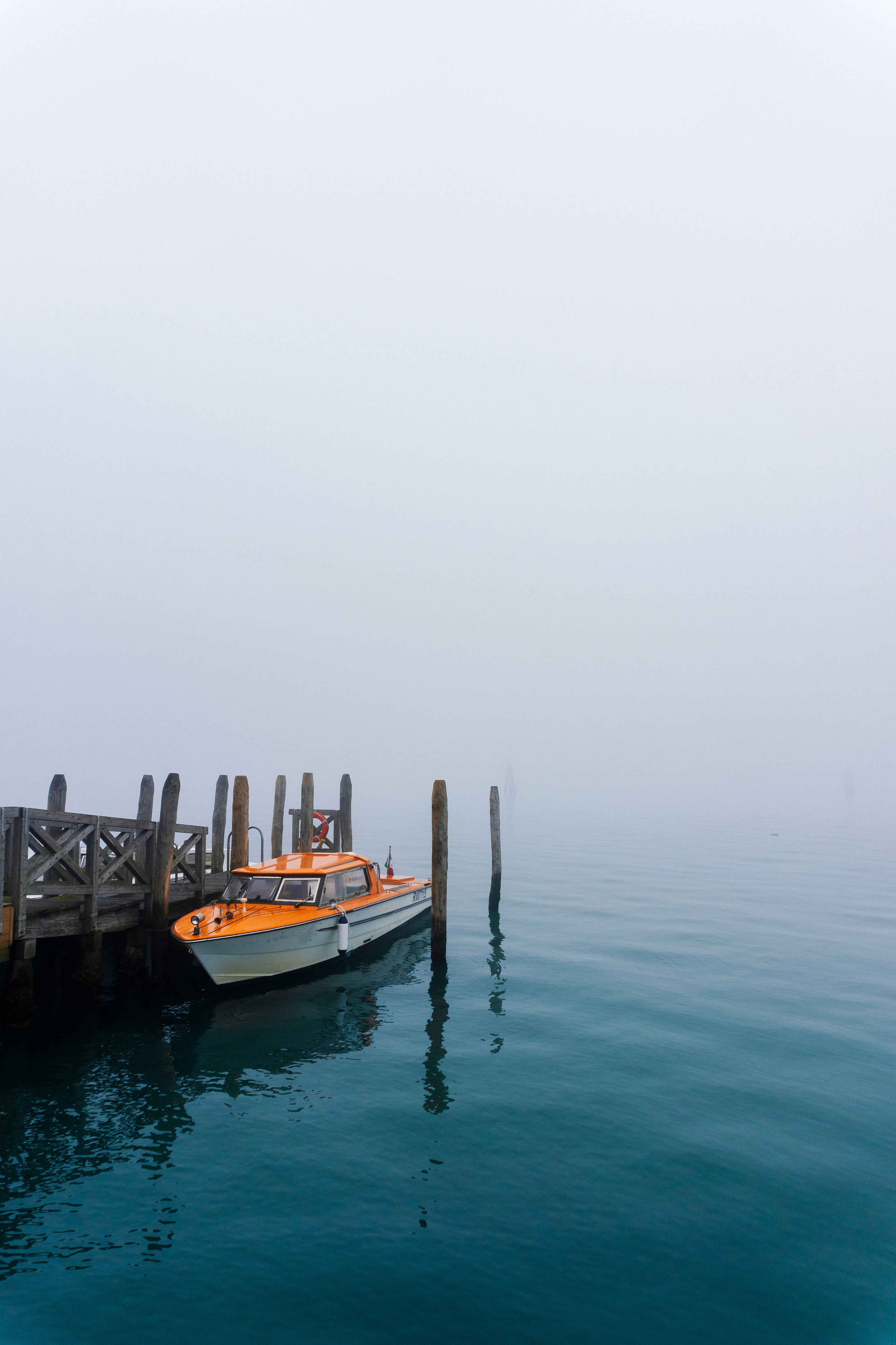 Boat floats at dock in foggy, misty water.