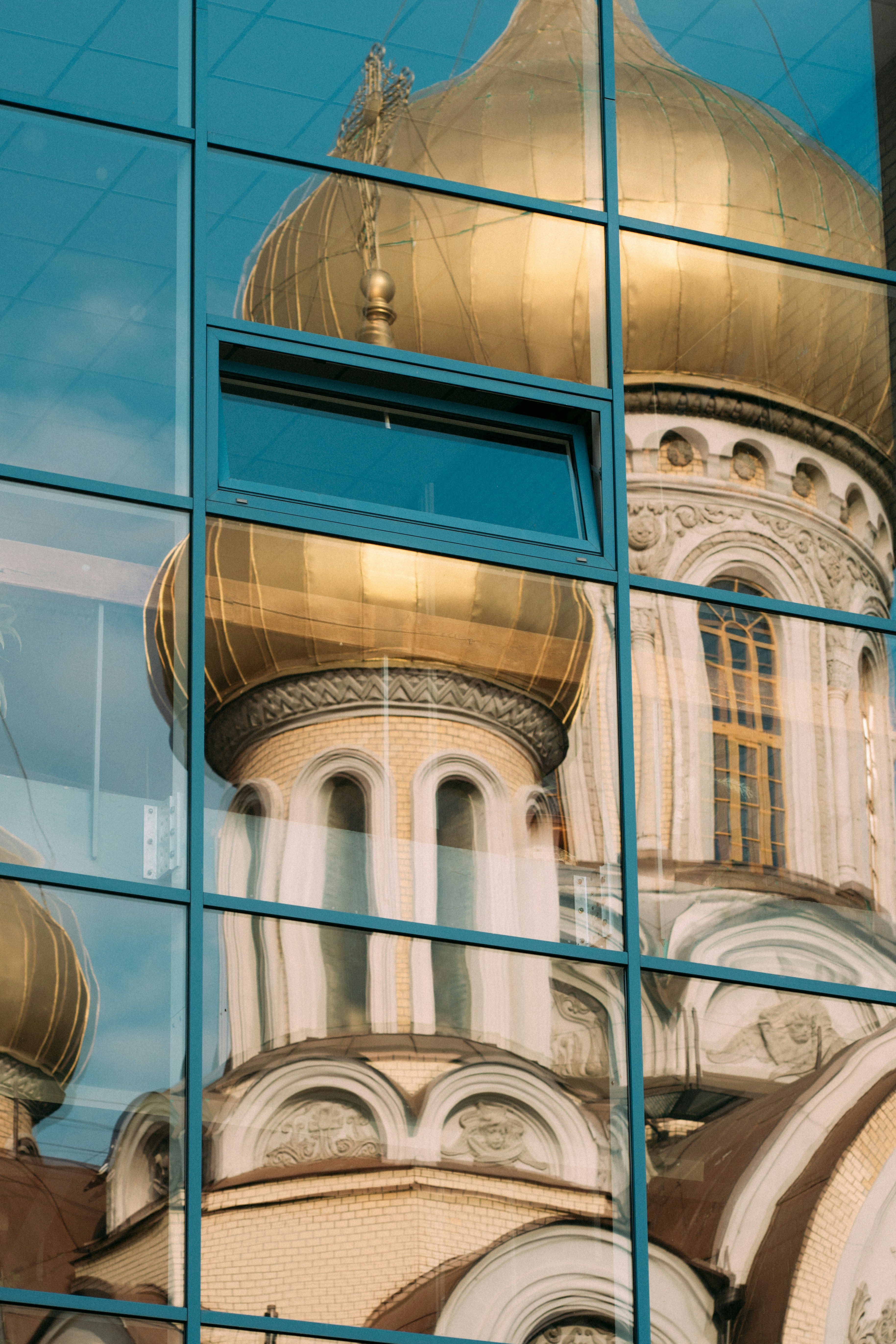 Church reflected in a modern building's glass facade.