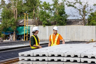 Construction workers inspect precast concrete slabs outdoors.