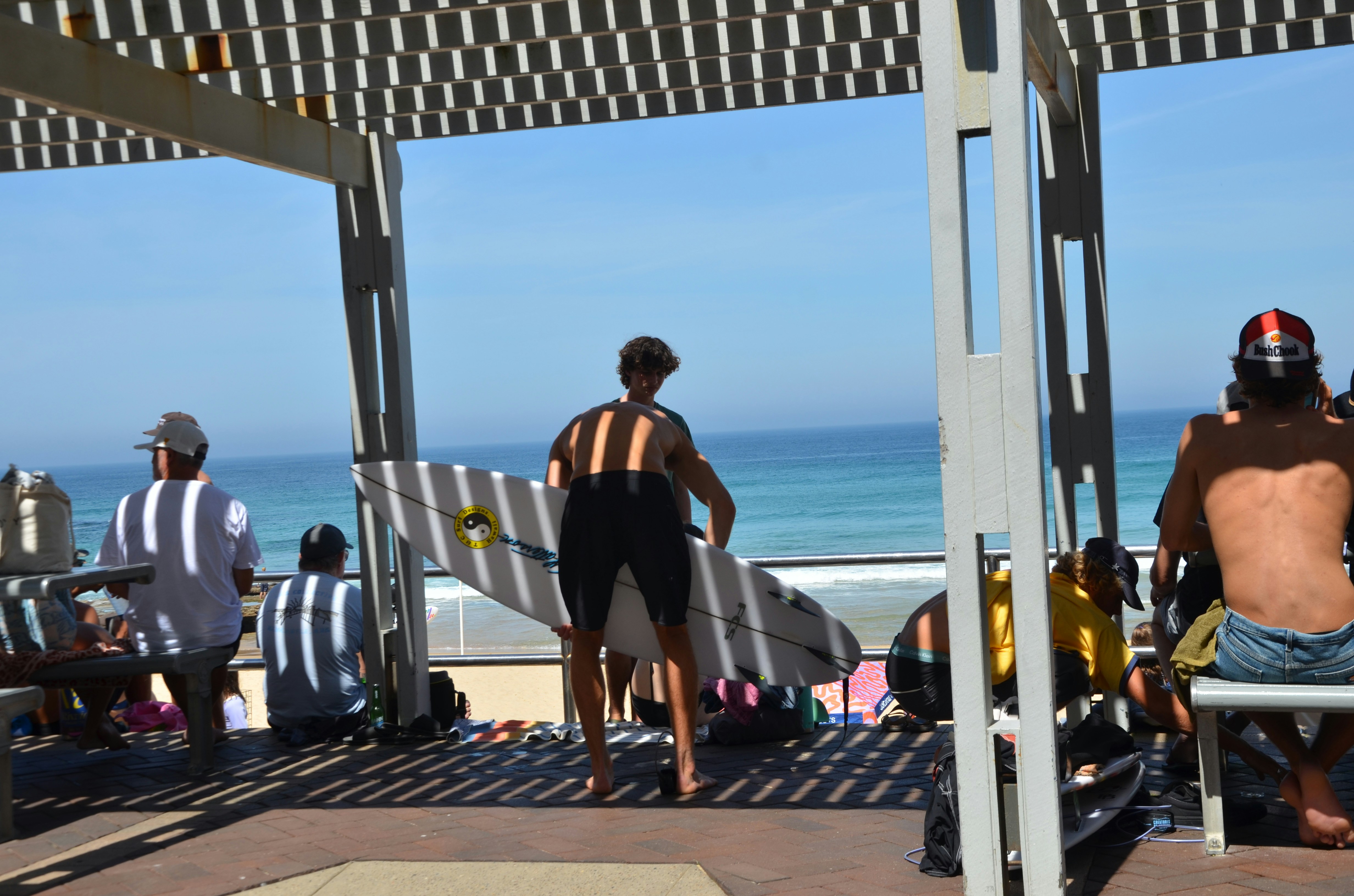 Surfers prepare to enter the ocean on a sunny day.