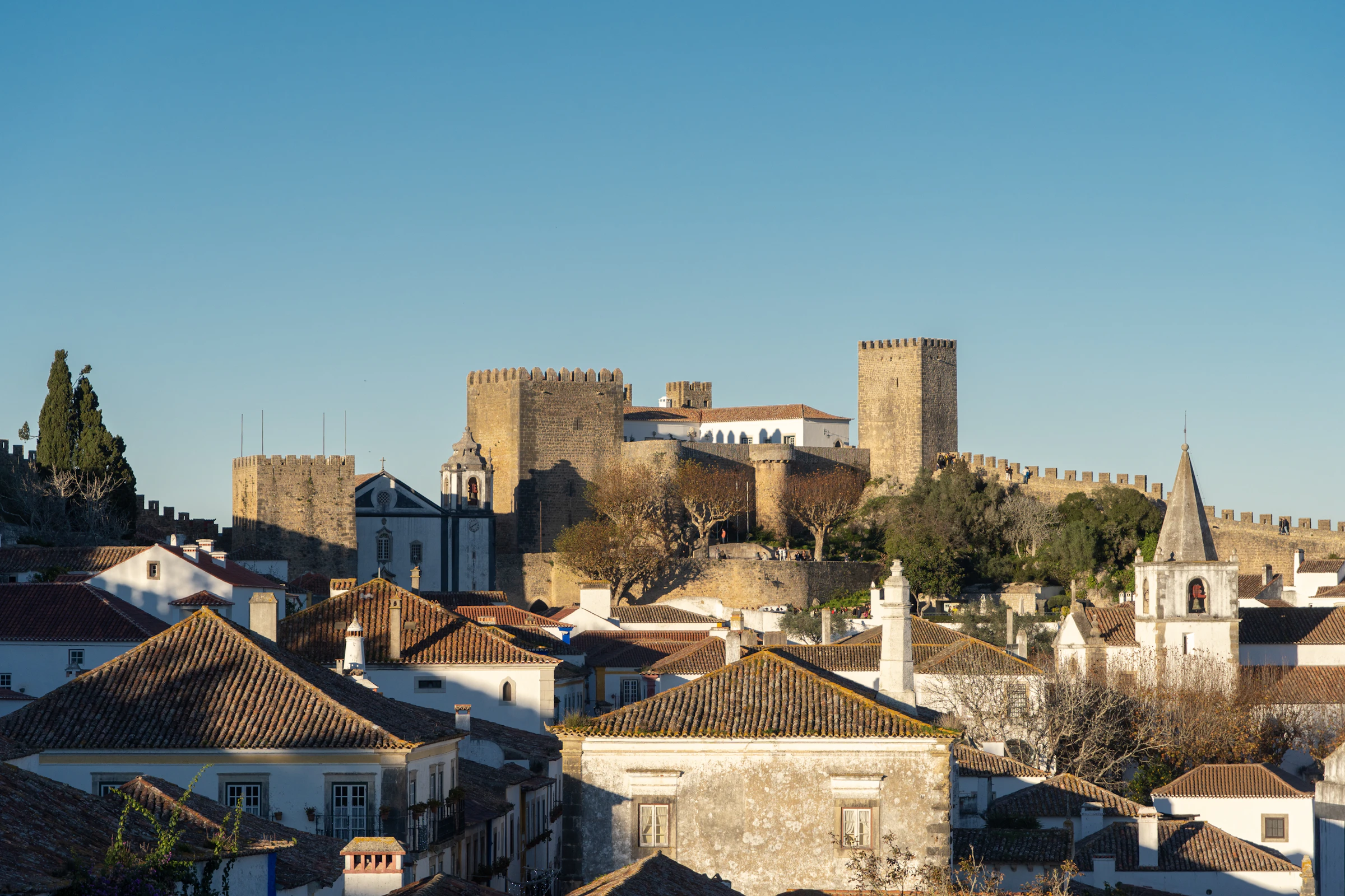 De ommuurde middeleeuwse stad Óbidos met haar witte huizen, het kasteel en de stadsmuren onder een blauwe lucht
