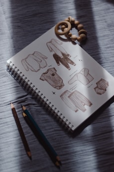 Sketchbook with baby clothes illustrations and crayons.