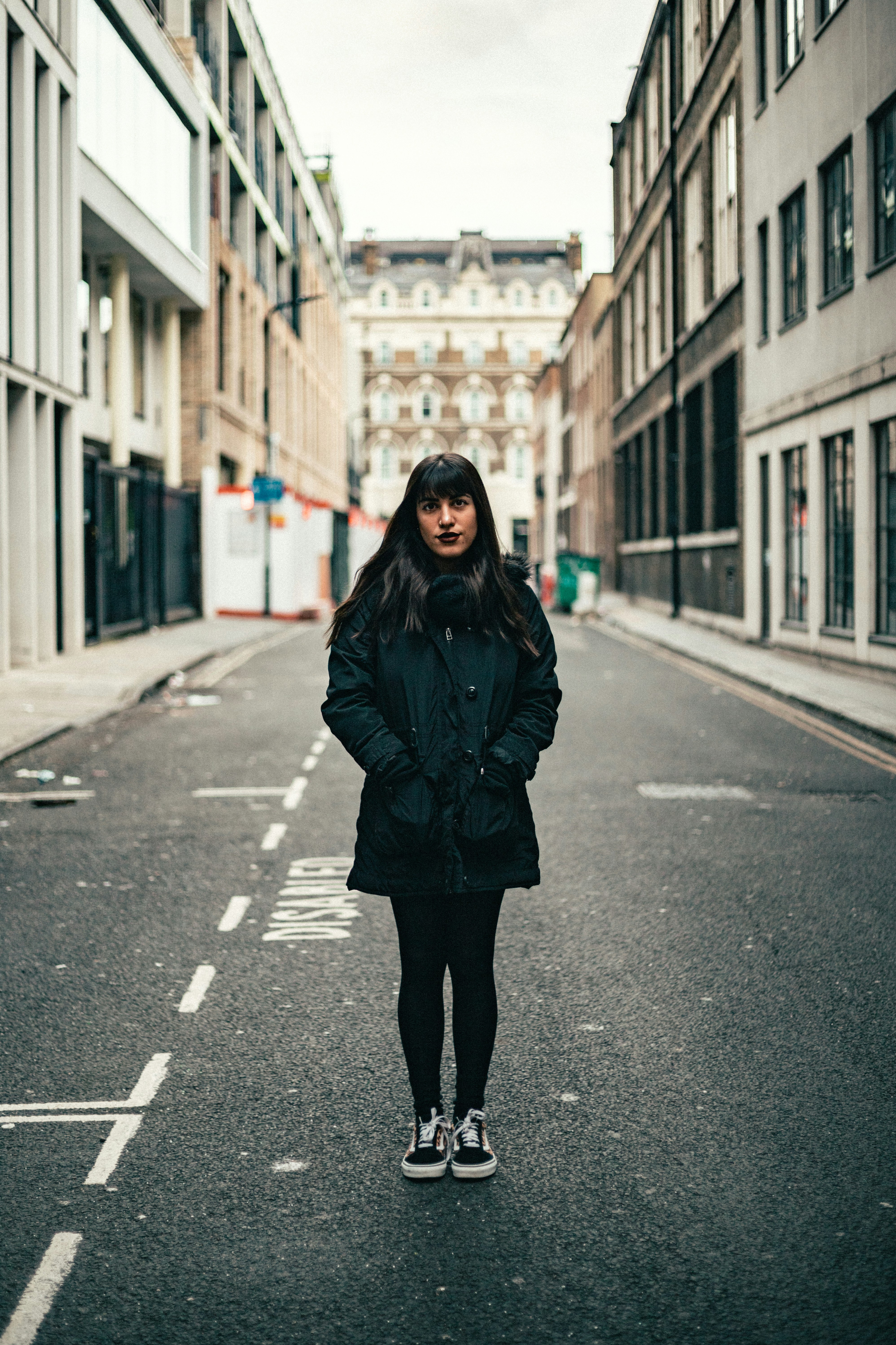 Mulher fica na rua, entre prédios.